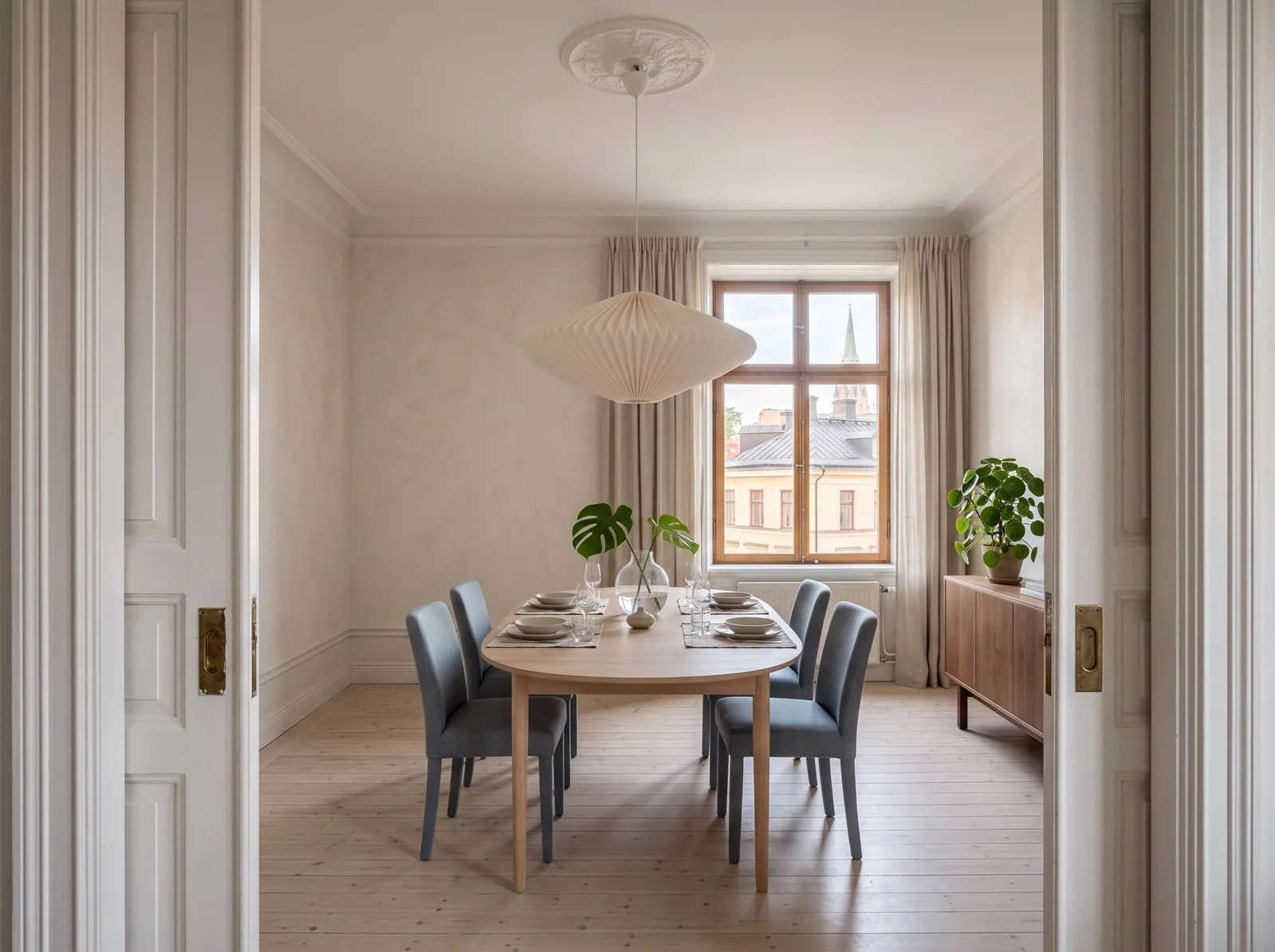 Dining room framed by double doors with a set table and tall window